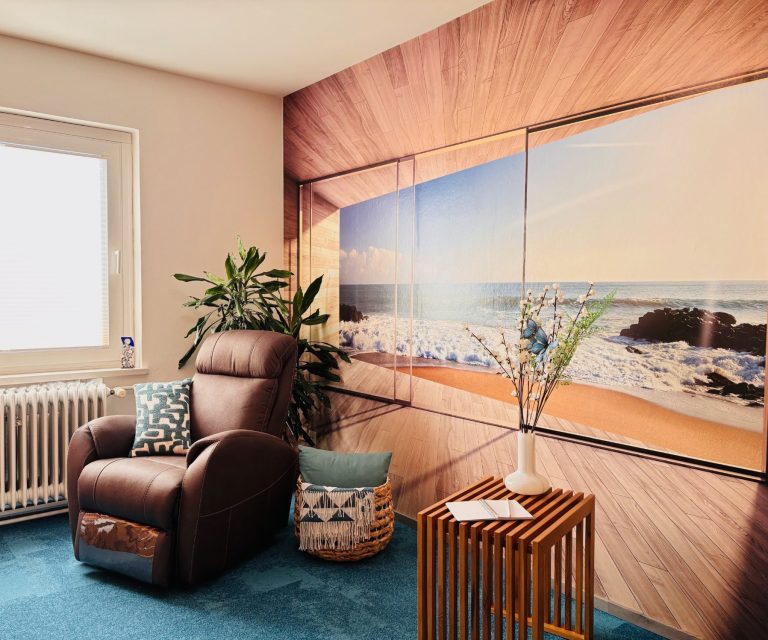 Ausstattung des Hypnoseraums Gemütlicher Raum mit braunem Sessel, Holzoptik-Wand und Meerblick-Dekor.